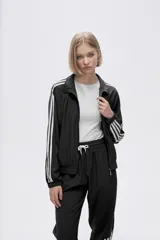 Campera deportiva verde con cierre frontal, cuello alto y tres rayas blancas en las mangas.
