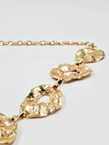 Cinturón dorado con cadena de eslabones y apliques con textura irregular.
