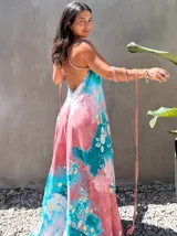 Vestido largo de tela fluida, color verde esmeralda con estampado abstracto en tonos turquesa y detalles dorados. Diseño asimétrico con un solo tirante tejido en el hombro.