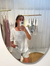 Remera blanca con panel central celeste, cuello redondo y mangas cortas. Presenta detalles de puntilla en el panel lateral.