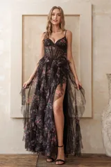 Vestido largo de fiesta negro con estampado floral multicolor, escote corazón, breteles finos, corpiño tipo corset con transparencias, falda con volados y tajo lateral.