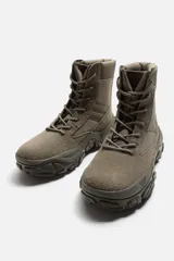 Zapatilla botín color gris, con combinación de piezas de piel y otros materiales en el corte. Cordonera con siete pasados y suela con volumen y diseño de textura.