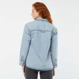 Sobrecamisa de denim celeste con cuello clásico, cierre frontal con botones a presión, mangas largas con puños abotonados, dos bolsillos de parche en el pecho y corte holgado.
