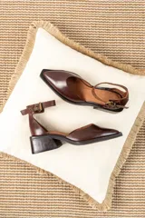 Zapato de cuero color marrón chocolate con punta cuadrada, corte lateral y pulsera al tobillo con hebilla dorada.