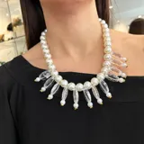 Collar de perlas plásticas blancas con detalles de resina transparente y herrajes dorados.