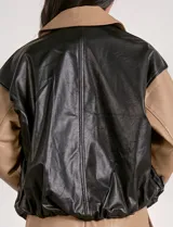 Campera bomber de cuero sintético negra con mangas color beige, cuello clásico y cierre frontal con cremallera.