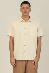 Camisa de manga corta color crema con textura, botones de madera y parche con logo.