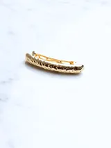 Broche dorado para el cabello con diseño texturizado.