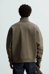 Sudadera negra de algodón con cuello alto y cierre de cremallera. Corte relaxed fit, manga larga y terminaciones en rib.