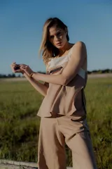 Conjunto de top y pantalón color beige. El top es de breteles anchos, con escote cuadrado y detalle de bordado en el frente. El pantalón es de corte recto y ancho, con bolsillos laterales y cintura con elástico y botones.