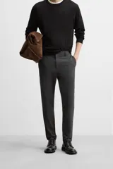 Pantalón negro de corte slim fit, confeccionado en tejido elástico. Cuenta con cintura elástica, bolsillos frontales y traseros de vivo. Cierre frontal con cremallera y botón.