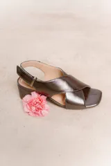 Sandalias negras de cuero con tiras cruzadas en el empeine, pulsera al tobillo con hebilla metálica y tacón cuadrado.