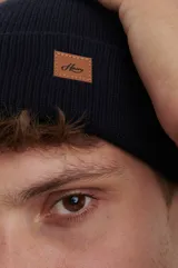 Gorro de lana azul con etiqueta de cuero con logo en el frente.