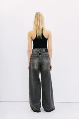 Jean oxford tiro alto de denim negro con lavado stone y bigotes. Pierna ancha desde la cadera.