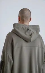 Canguro verde militar de algodón rústico, corte oversize, con capucha forrada, bolsillo tipo canguro y bolsillo en la manga con cierre.