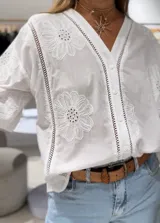 Camisa blanca de manga larga con puños elásticos y cierre frontal con botones. Detalles de bordados perforados combinados a tono en parte delantera y trasera.