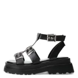 Sandalias bajas color beige con plataforma y tiras anchas con hebillas plateadas, estilo romano.
