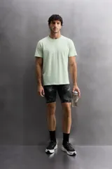 Camiseta deportiva verde claro confeccionada en tejido técnico, ligero y elástico en cuatro direcciones. Tiene cuello redondo, manga corta, zonas con estructura perforada y logo estampado.
