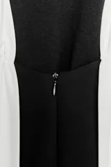 Minivestido negro con cuello halter y espalda descubierta. Presenta un panel blanco en la parte superior delantera y forro interior.