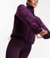 Campera deportiva de terciopelo color violeta, con cuello alto, cierre de botones, bolsillos laterales y puños ajustados.