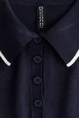 Remera polo azul marino de punto fino, corte entallado, con cuello clásico, tapeta de botones y mangas cortas con ribete blanco.