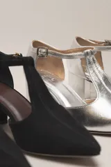 Zapato de vestir negro de cuero, con punta fina, tira en forma de T y hebilla lateral.