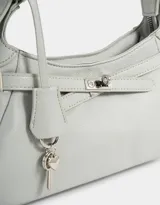 Bandolera de cuerina color gris claro, con correa de hombro ajustable, cinturón frontal decorativo y charm lateral con forma de mariquita.