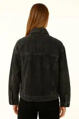 Campera de jean azul con cuello clásico, cierre frontal con botones dorados, bolsillos con solapa abotonada en el pecho y corte holgado.