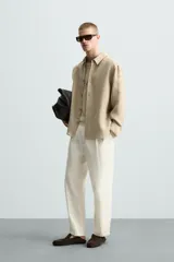 Camisa de manga larga color celeste claro, con cuello solapa y cierre frontal de botonadura. Presenta una textura sutil en el tejido.