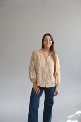 Camisa color beige con bordados florales blancos, cuello mao, mangas largas con elástico en los puños y cierre frontal con botones.