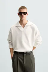 Sweater color crema de punto con cuello polo y escote en V.