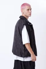 Chaleco negro con estampado de logos, cierre desmontable, broches snap ocultos, bolsillos frontales, elástico con tanca en la cintura e interior de tafeta relleno de guata.