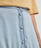 Pollera midi de liocel celeste, con corte evasé y tres niveles de volantes. Presenta abotonadura frontal completa y ruedo desflecado.