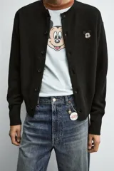 Cárdigan negro de punto con cuello redondo y manga larga. Tiene un parche de Mickey Mouse © Disney en el frente. Cierre frontal con botones.