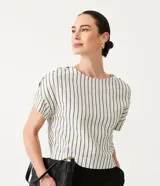 Blusa de algodón color blanco con rayas verticales negras, cuello redondo y botones decorativos en los hombros.