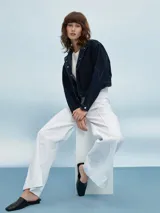 Campera corta de jean azul oscuro con costuras en hilo color crema, cuello mao y cierre con botones metálicos.