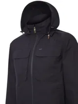 Campera cortaviento negra con capucha desmontable, cierre frontal con broches imantados, cuatro bolsillos frontales con solapa y ajuste en el ruedo.