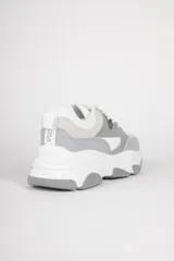 Zapatillas blancas con recortes en diferentes tonos de gris, cordones y plataforma irregular de 5cm.