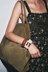 Pack de dos pulseras rígidas articuladas realizadas en resina: una marrón con detalles dorados y otra color hueso con alambre dorado enrollado.