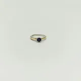 Anillo solitario en plata y oro con circonia violeta redonda engarzada.