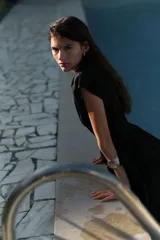 Vestido corto negro sin mangas en tejido fresco de algodón. Modelo con escote cruzado en V, pliegues en los hombros, cintura fruncida y pollera con vuelo.