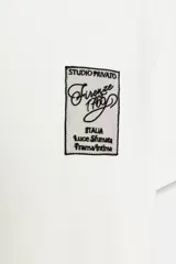 Camiseta blanca de algodón con cuello redondo y mangas cortas. Estampado frontal con texto "Meet me at Palais Lomtam, 7, Passage des Rêveries" enmarcado en un diseño ondulado.