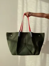 Bolso negro tipo tote de neopreno con bolsillo interno de red, sobre haciendo juego y gancho para sujetarlo.