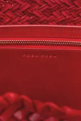 Bolso tipo tote de cuero vacuno, completamente trenzado a mano. El color es marrón oscuro, casi chocolate. Posee dos asas de hombro trenzadas.