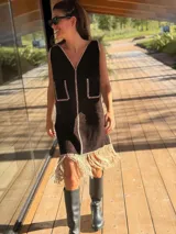 Vestido corto marrón de gamuza sintética, sin mangas, con escote en V y detalle de flecos en el ruedo. Presenta apliques bordados en el frente y laterales.