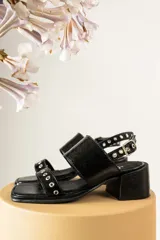 Sandalias de tacón de madera con tiras de gamuza marrón y detalles de tachas metálicas.