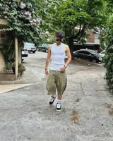 Bermuda de corte baggy color verde con efecto gastado. Presenta costura vertical trasera en cada pierna y detalle artesanal visible en el bajo. Incluye un cordón extra confeccionado en la misma tela.