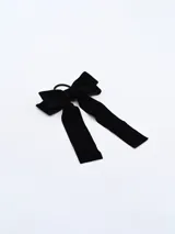 Moña (lazo) de terciopelo negro, con dos cintas largas colgantes, sujeta a una goma elástica para el cabello.