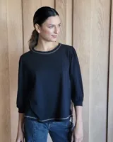 Remera blanca de mangas 3/4 abullonadas, cuello redondo y corte holgado.