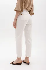 Jean gris lavado, estilo mom fit, con aplique fruncido en forma de espiral en la pierna izquierda, tiro alto, bolsillos delanteros y traseros funcionales, y cierre frontal con botón y cremallera.